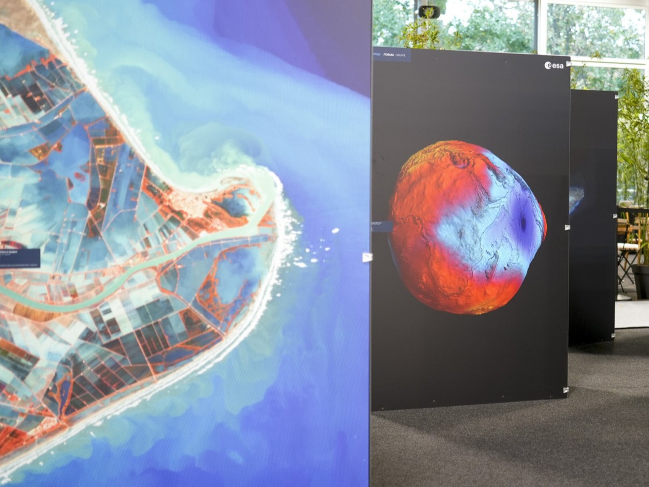 Pannelli espositivi raffiguranti immagini satellitari della Terra, tra cui una mappa costiera e un modello geoidale colorato