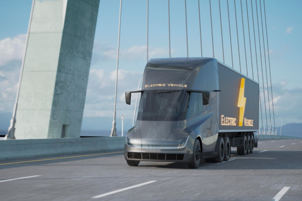 un moderno camion merci con su scritto 'electric vehicle' che attraversa un ponte