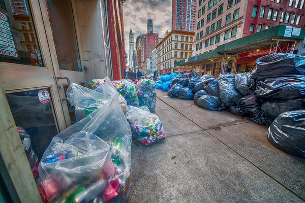 una via di new york completamente invasa da decine di sacchi di spazzatura che occupano tutta la strada