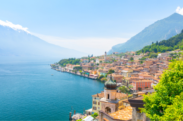 visione dall'alto di un tipico paese italiano in riva al lago di Garda durante una soleggiata giornata con alte montagne all'orizzonte