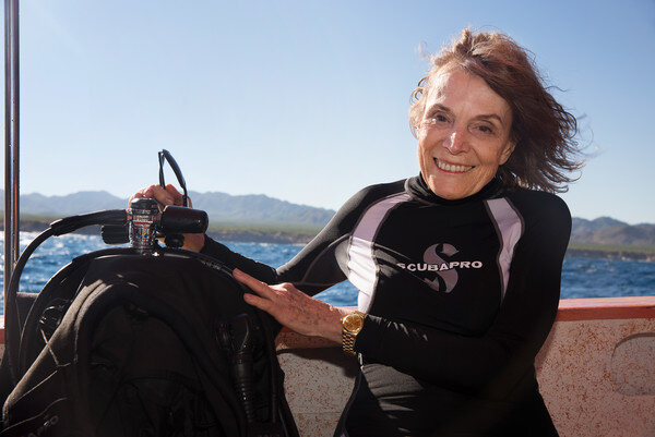  photo of sylvia earle smiling in a wetsuit next to a scuba oxygen tank