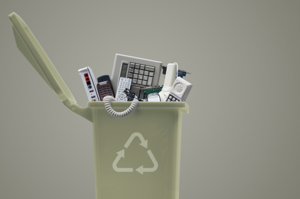 un cestino della spazzatura con il simbolo del riciclo con all'interno apparecchi informatici come computer e telefoni