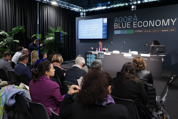 conferenza durante ecomondo sulla blue economy con un pubblico che ascolta seduto in platea e un relatore che parla al microfono