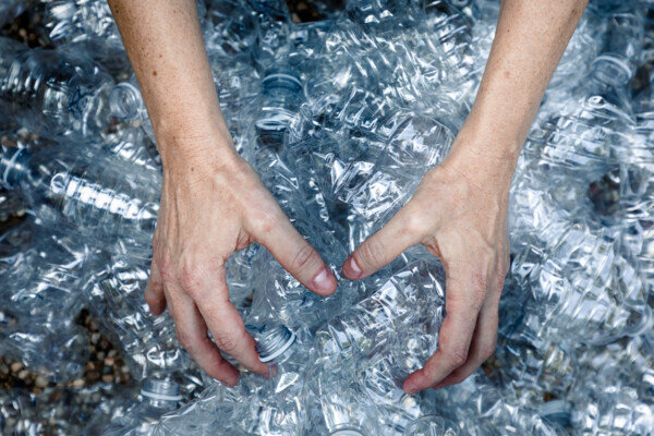 due mani afferrano bottiglie di plastica usate