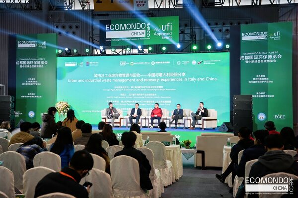 una conferenza durante ecomondo china con cinque relatori sul palco con un grande pubblico davanti