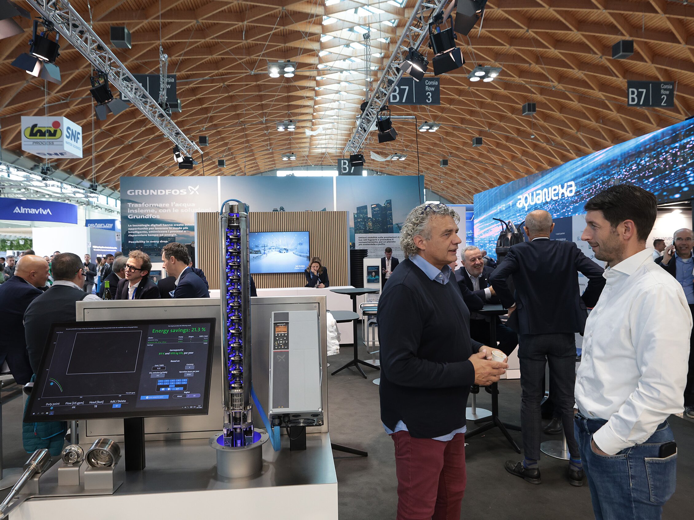guests at Ecomondo talk with each other surrounded by machinery and displays from the Almaviva, Grundfos, and aquaVEXA stands