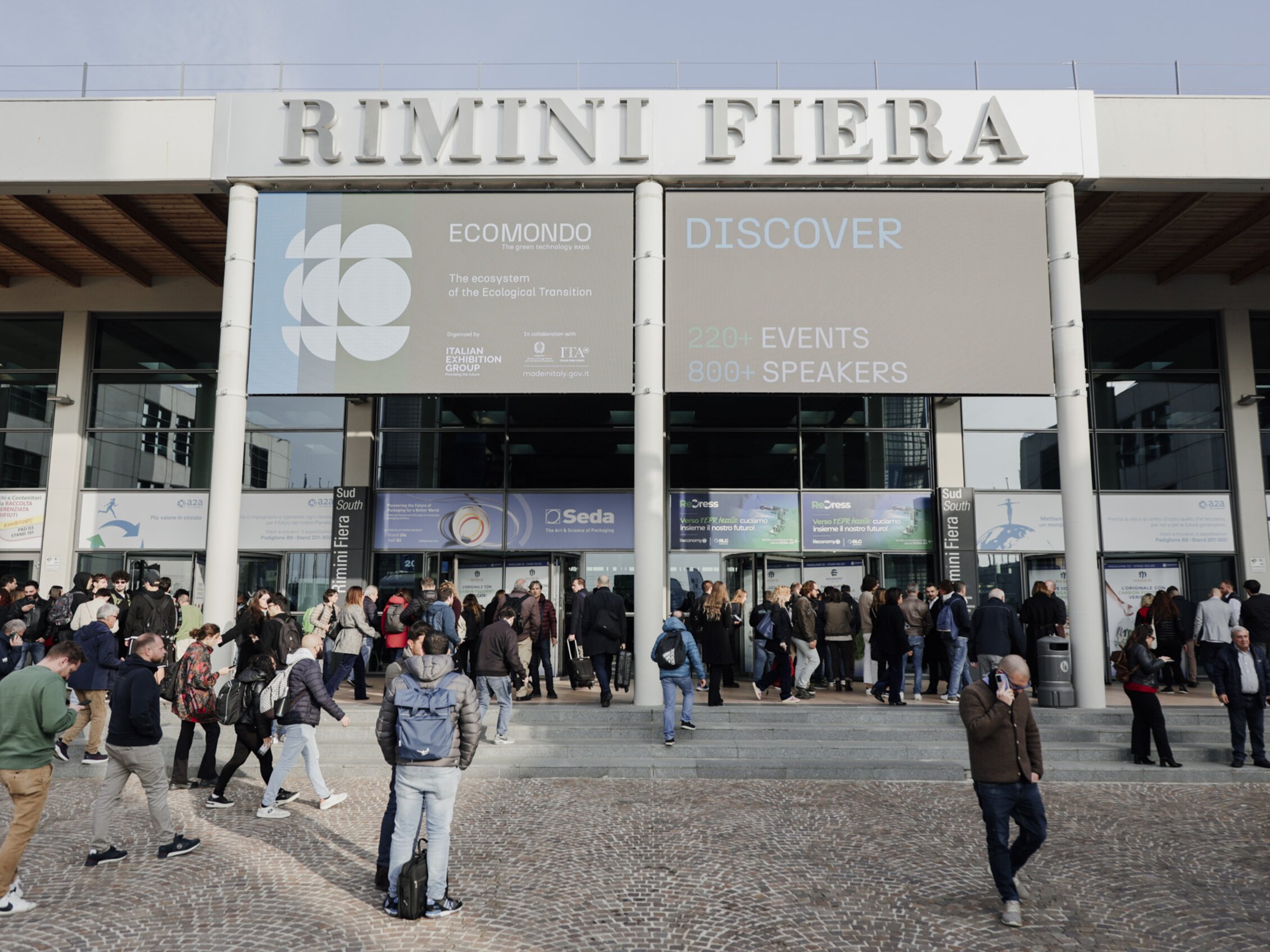 molte persone che entrano in uno degli imponenti ingressi della fiera di rimini